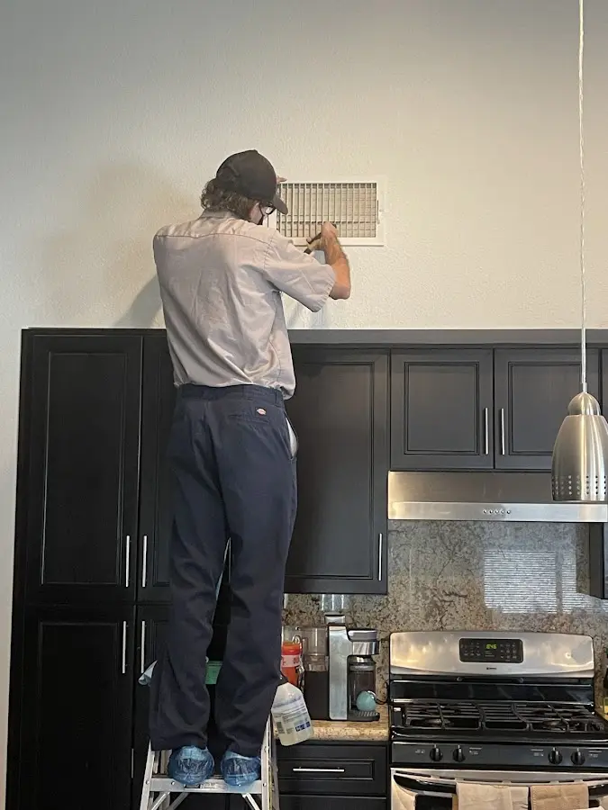 Technician inspecting an air vent during HVAC service in Painesville